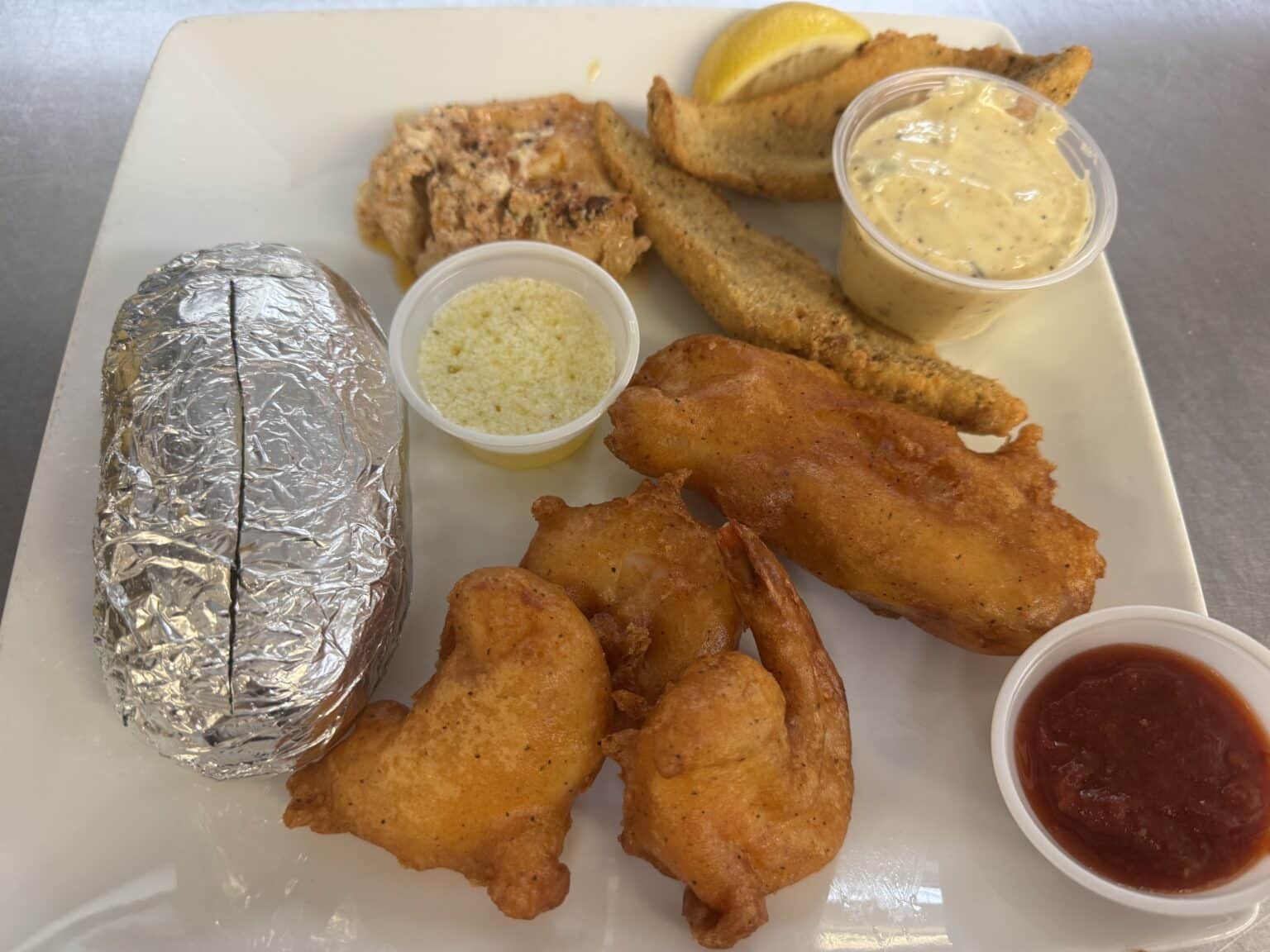 Fish and shrimp dinner with baked potato and dipping sauces.